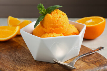 Balls of tasty orange sorbet, fresh fruit, mint and spoon on table, closeup