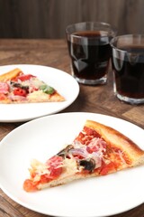 Slices of tasty pizza with thin smoked sausages served on wooden table, closeup