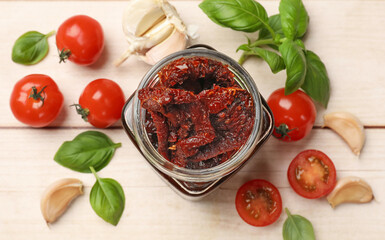 Delicious sun dried tomatoes, fresh vegetables, basil and garlic on white wooden table, flat lay