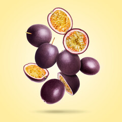 Delicious ripe passion fruits falling on pale yellow gradient background