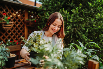 Young woman taking care of plants with water can and mister	