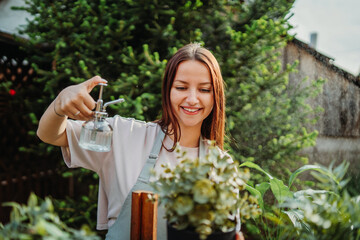 Young woman taking care of plants with water can and mister	
