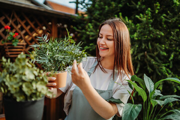 Young woman taking care of plants with water can and mister	