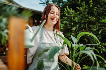 Young woman taking care of plants with water can and mister	