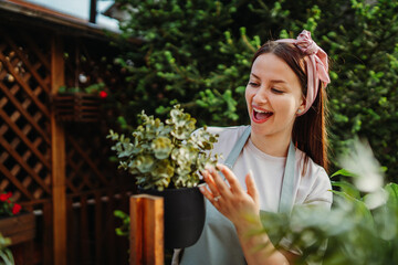 Young woman taking care of plants with water can and mister	