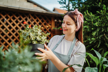 Young woman taking care of plants with water can and mister	