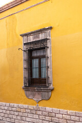 Obraz premium Ventana vertical antigua con muro de piedra enmarcada. Espacio viejo, exterior de casona colonial mexicana. Hacienda historica. Muro amarillo.