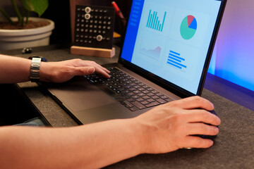 Businessman working with statistical data on laptop, analyzing graphs and charts in modern office environment