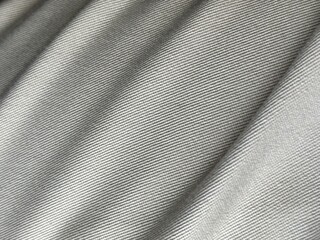 Close-up of khaki textile fabric with a smooth texture and subtle folds, showcasing the fine weave and natural color. Ideal for fashion and abstract background design