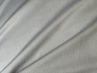 Close-up of khaki textile fabric with a smooth texture and subtle folds, showcasing the fine weave and natural color. Ideal for fashion and abstract background design