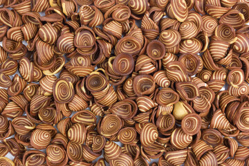 A top-down full frame view of numerous "Kuping Gajah" Indonesian traditional cookies. These crispy, thin cookies are characterized by their distinctive spiral pattern of light and dark brown.