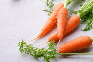 Organic mini carrots with leaves isolated on white wood background.