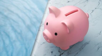 Pink piggy bank by the pool on a beautiful sunny day - vacation savings concept