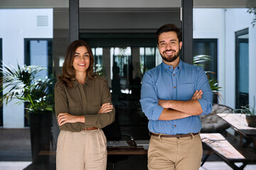 Team of two business partners executives standing in office looking at camera. 2 sales managers, company agents, consultancy professionals, entrepreneurs posing arms crossed for corporate portrait.