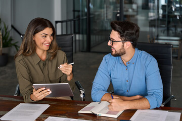 Smiling professional colleagues at having conversation working together with tab device technology...