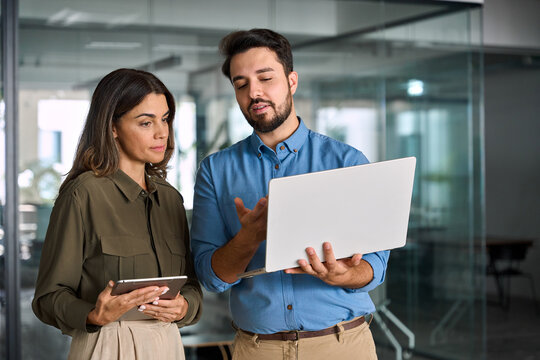 Busy female executive manager talking to male colleague having conversation showing software online solution on laptop. Two professional business people working in office with computer. - Powered by Adobe