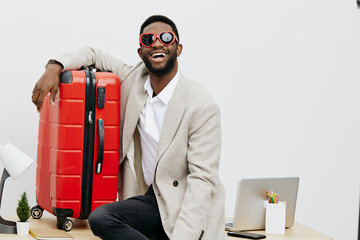 Smiling man with dark hair and beard wearing stylish beige blazer and red sunglasses holding red...