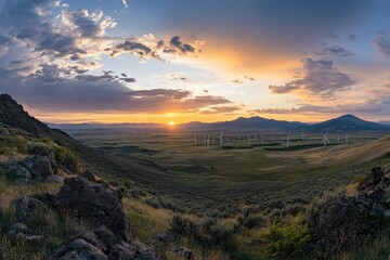 Obraz premium Sunset over a valley with windmills; hills flank the horizon