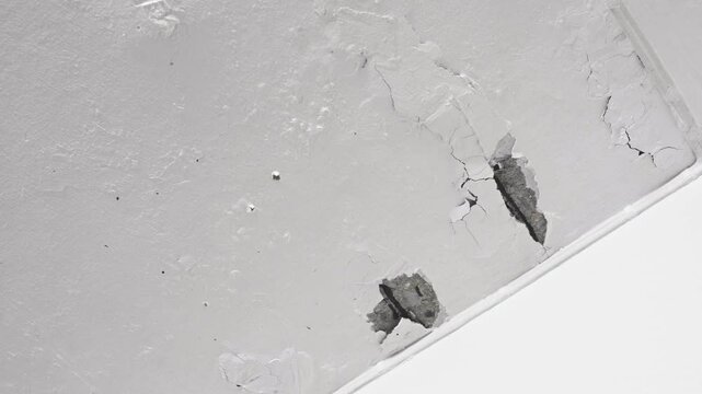 The ceiling and walls of the house are moisture damaged, with peeling paint, cracks, and rough surfaces. The plaster to erode and peel off.