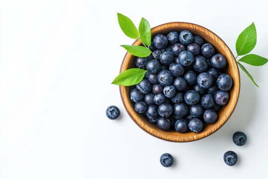 A wooden bowl filled with fresh blueberries and green leaves, isolated on white background