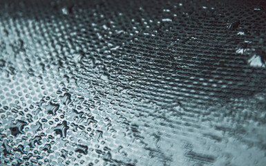 Rain drops on a glass, reflecting light in an artistic pattern. Abstract water droplets forming a mesmerizing pattern on a surface. Close-up of a textured surface with droplets of water glistening