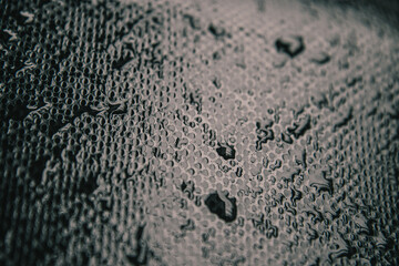 Fabric surface with moisture droplets in macro view. Abstract of water droplets on textured fabric.Water droplets forming patterns on fabric material. Moisture droplets on textured fabric surface