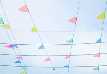 Minimalist style photo of colorful flags fluttering in the wind against a beautiful natural clear sky backdrop.