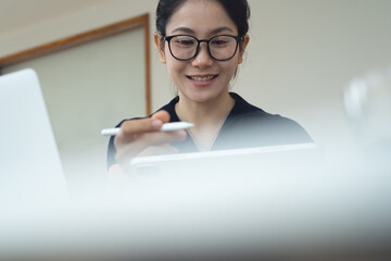 Asian business woman using digital tablet and laptop computer for online meeting during remote...