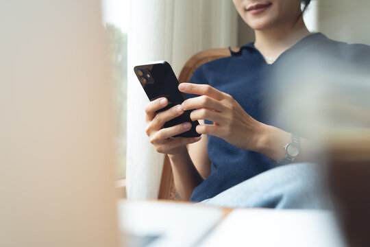 Woman using mobile phone and laptop checking email or news online while sitting at home. Searching internet social networks or remote working at coffee shop, business casual, closeup
