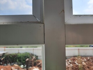 Window detail from inside a building showing construction debris and countryside environment outside