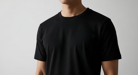 Close up of a person wearing a plain black t shirt against a white backdrop