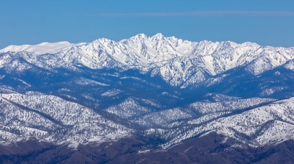 Obraz premium Snowy mountain range against blue sky