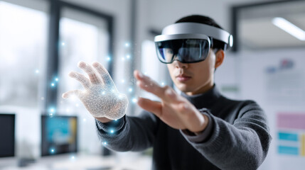 Young man in augmented reality headset interacting with a glowing digital hologram in a modern bright office.
