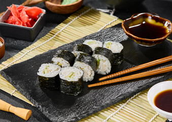 Avocado hosomaki sushi rolls on black slate, bright lighting, vibrant minimalistic composition