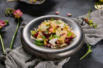 Beetroot, apple and cheese salad on a matte grey plate, showcased in moody lighting and minimalist composition