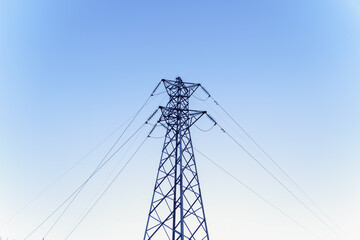 Metal electricity pylon standing tall against a clear blue sky, conducting power through its...