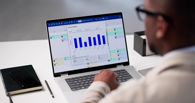 African American Project Manager Analyzing Resource Charts - Powered by Adobe