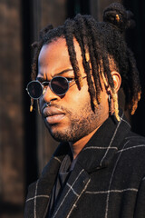 Portrait of stylish black man with dreadlocks in buns