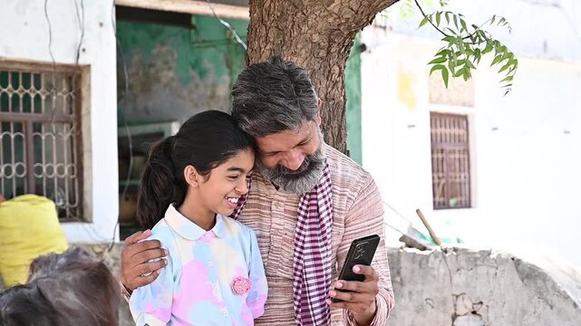 Happy rural indian father and child daughter use smart phone together. Village people Digital india. Wireless technology