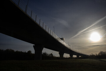 Dramatic low-angle view of a modern bridge silhouetted against the early morning sun