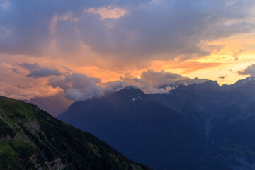 Fototapeta premium Mountain panorama with Rhone Valley and red sunset with burning sky and alpenglow in Swiss Alps, Switzerland