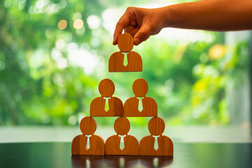 Employees forming a pyramid model with a hand selecting the top figure, symbolizing the importance...