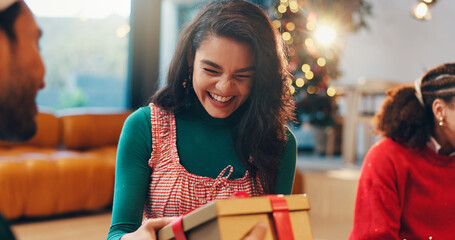 Happy, gift giving and friends in home for christmas event, party or celebration together. Excited, woman and people with presents for secret santa tradition on xmas eve for festive holiday in house.