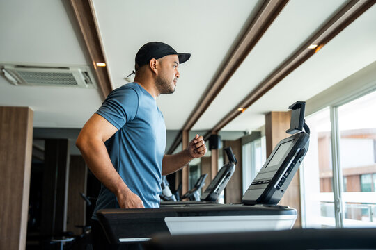 Young asian man runner exercise indoor gym. fitness man jogging wearing sportswear. Athlete man in sportswear Workout running on the treadmill. - Powered by Adobe