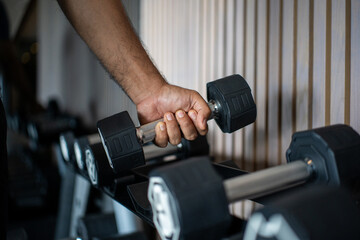 Young asian man weight training wearing sportswear. Asian exercise indoor gym lifting dumbbell....