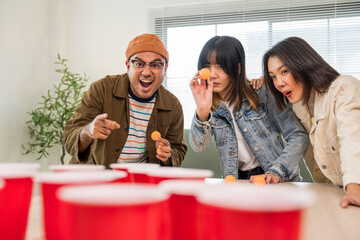 Office leisure group and board games. Happy asian diverse group friends playing together with beer ping pong at home office standing at the table enjoying time together.