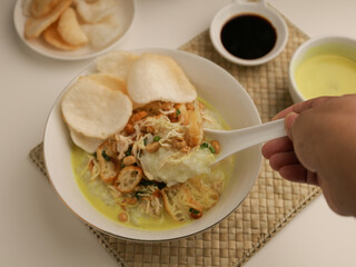 Rice porridge in a bowl, served with shredded chicken, chicken stock, fried shallot and crackers