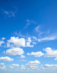 Bright blue sky with scattered white fluffy clouds and wispy cirrus clouds on a clear day