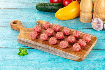 Raw beef meatballs over board