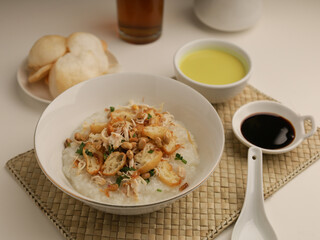 Rice porridge in a bowl, served with shredded chicken, chicken stock, fried shallot and crackers